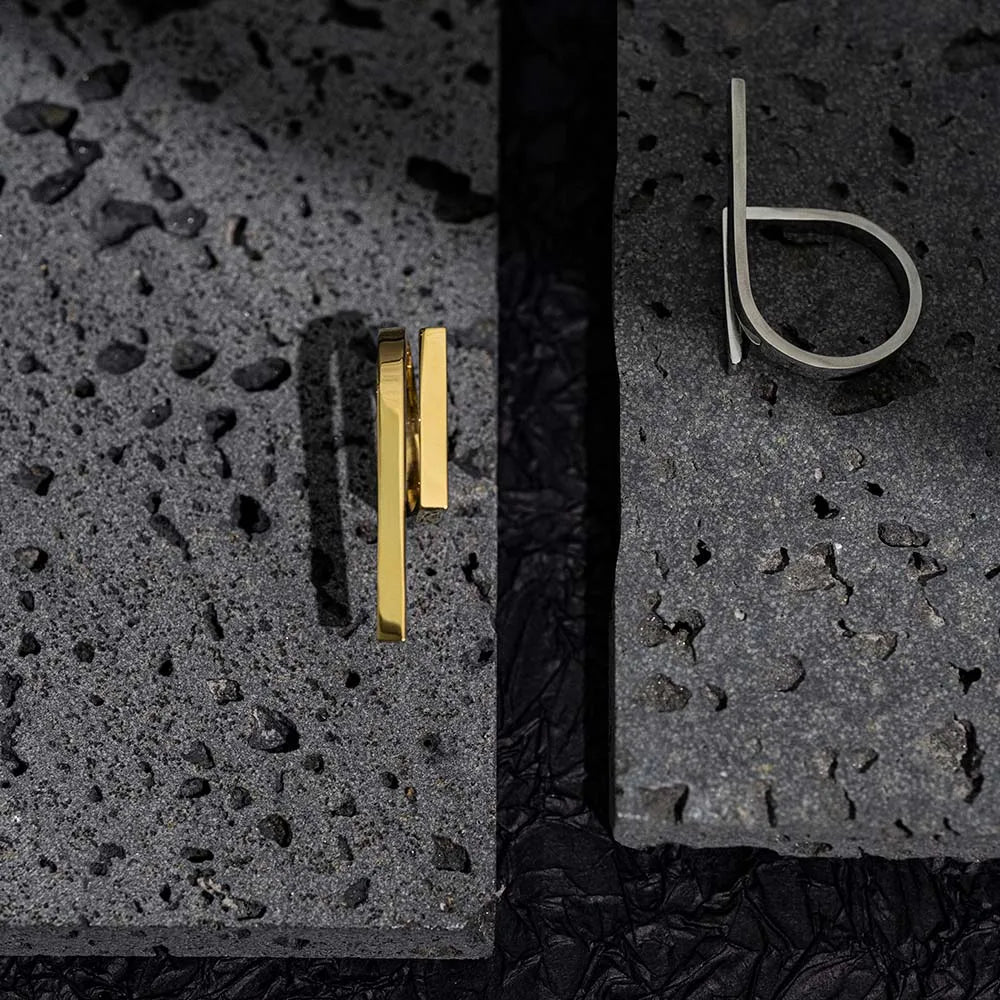 geometrisk ring i titan stål guld och silver minimalistisk design liggandes bredvid varandra