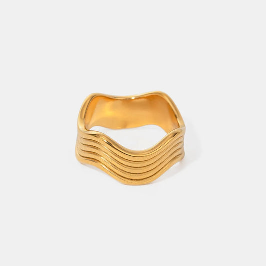 vågformad ring i rostfritt stål guld minimalistisk design mot vit bakgrund